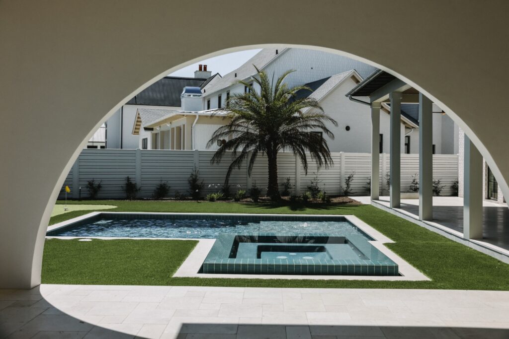 Architectural 30A pool courtyard framed by arch and palm